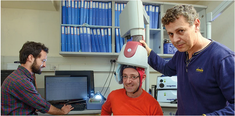 ابراهام زنگن، عصب شناس (راست) و دو نفر از دانشجویانش با نسخه اولیه سیستم تحریک مغناطیسی جمجمه ای مکرر